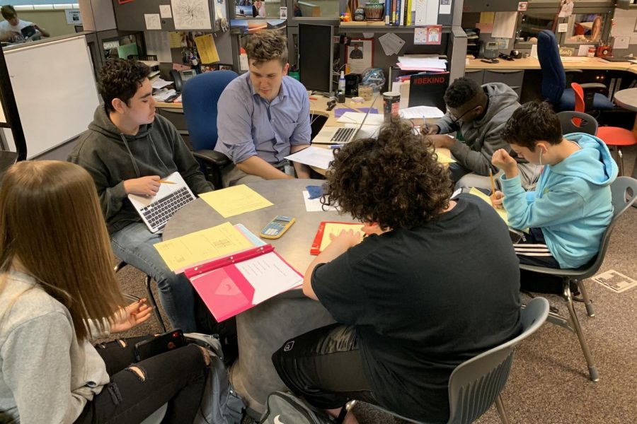 Math Instructor Steven Emmerich sits at his crowded desk and helps students during his open mods.