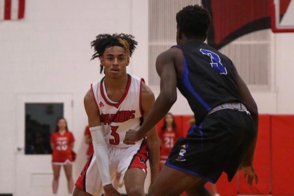 Senior, PJ Ngambi dribbling the basketball while Junior, Justin Sitti from Creighton Prep gaurds him.