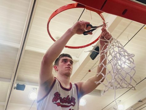 Senior Tate Odvody cuts down the net after the 83-76 overtime win against Lincoln High. 