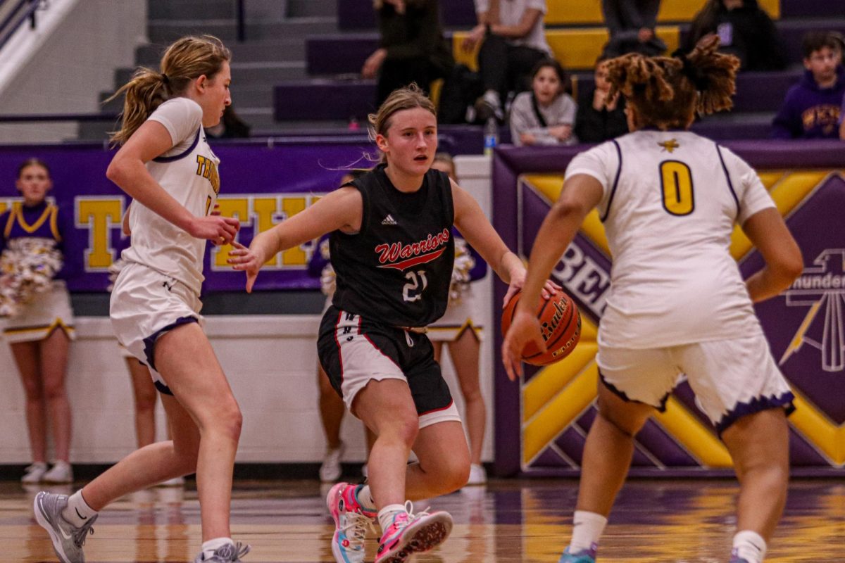 Senior Sydney Hagen makes it past two Bellevue West defenders. The Warriors went on to win the game 80-76.